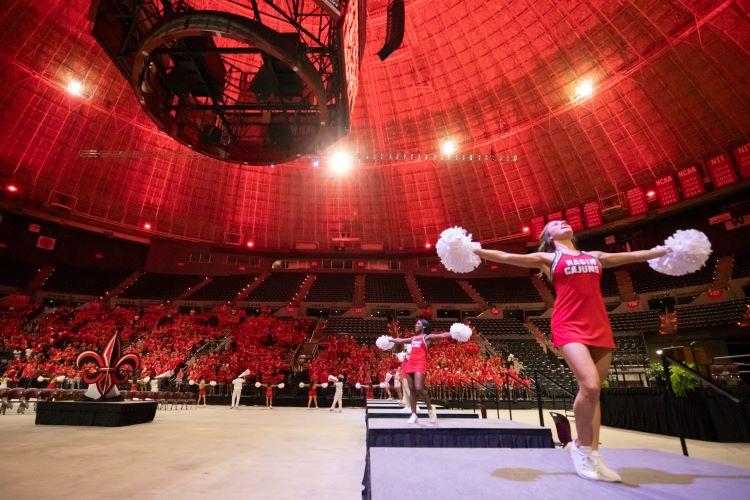 Cheerleader leading chants for students in the Cajundome at New Student Convocation