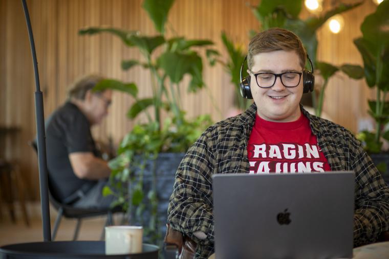 Online student studies on laptop in a coffee shop