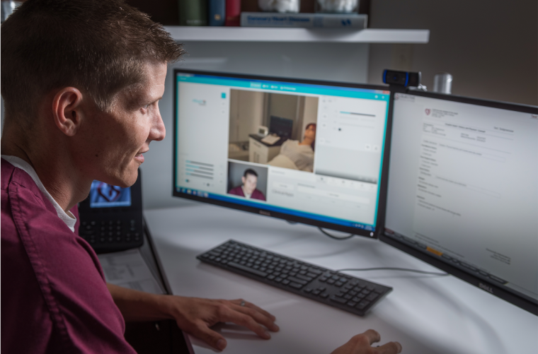 Nurse wearing maroon scrubs works on coursework on a computer