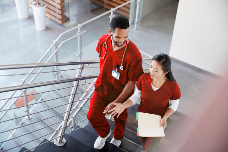 Two nurses wearing red scrubs in discussion