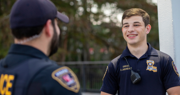 Two UL Lafayette campus police officers smile in conversation at the Student Union.