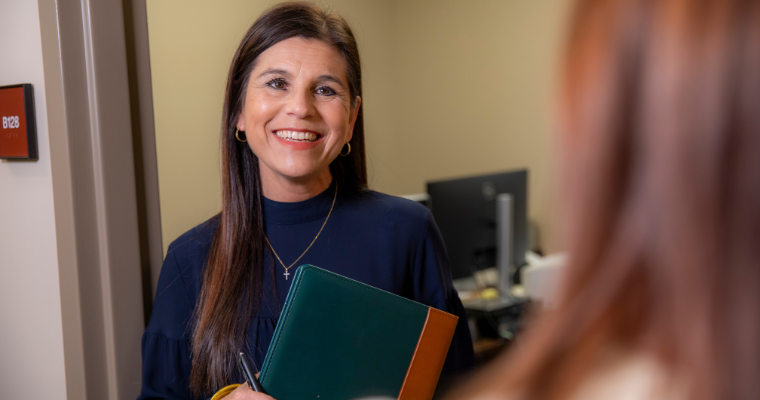 Lea Guidry, Director of Acadiana Tumor Registry, smiles while speaking with a colleague. 