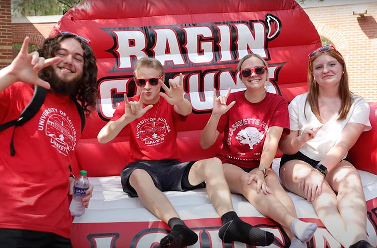 UL Lafayette students sitting on an inflatable Ragin' Cajuns chair