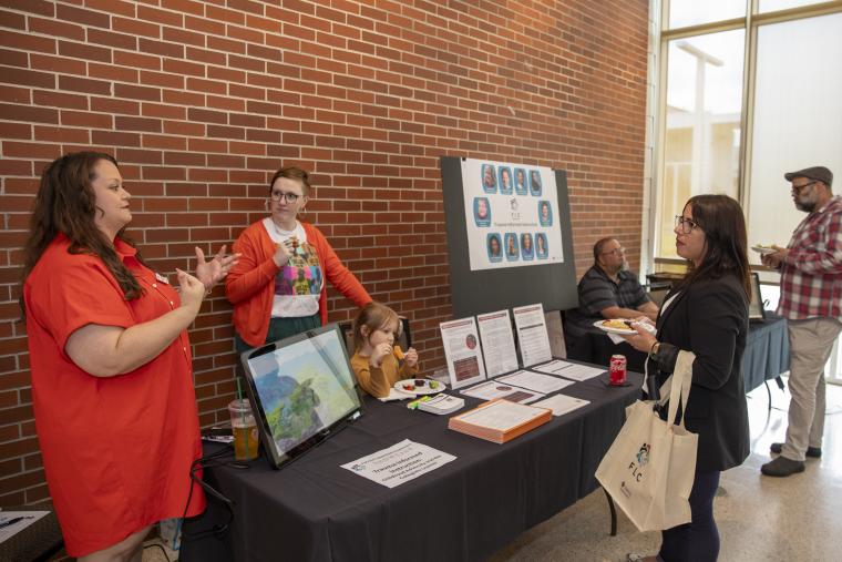 FLC members present research regarding trauma-informed teaching practices to an attendee during the FLC Showcase.