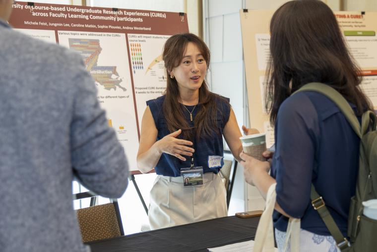 A woman is pictured presenting research in front of a poster display during the 2025 FLC Showcase.