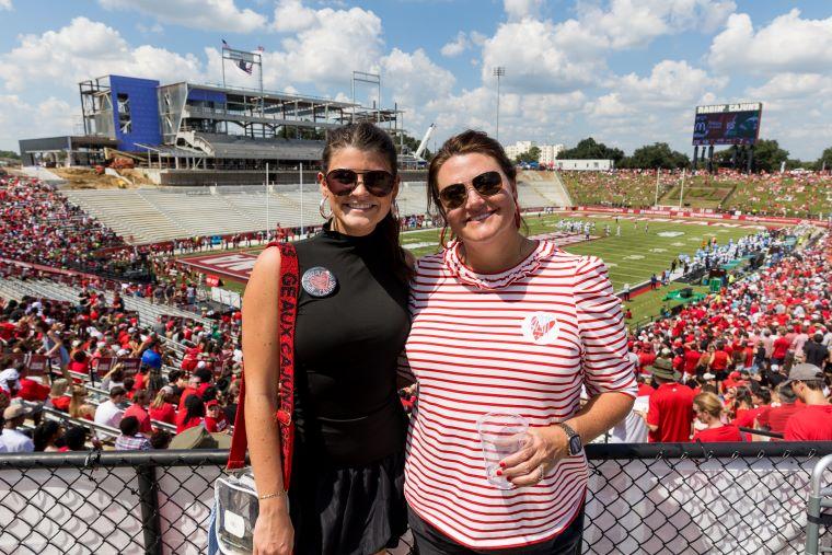 A student and her mom wear Ragin' Cajuns colors and accessories, pose in front of Cajun Field during a football game