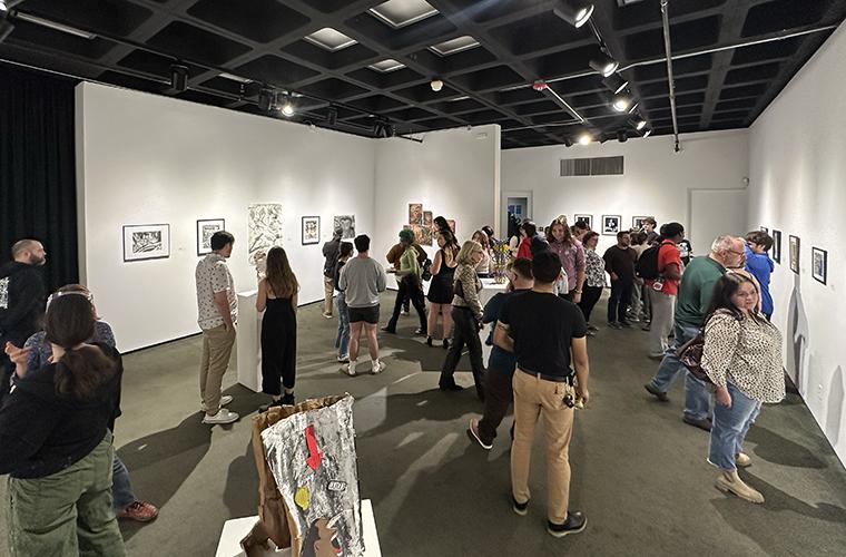 A crowd moves through the large halls of Fletcher Hall Gallery as they inspect the artwork