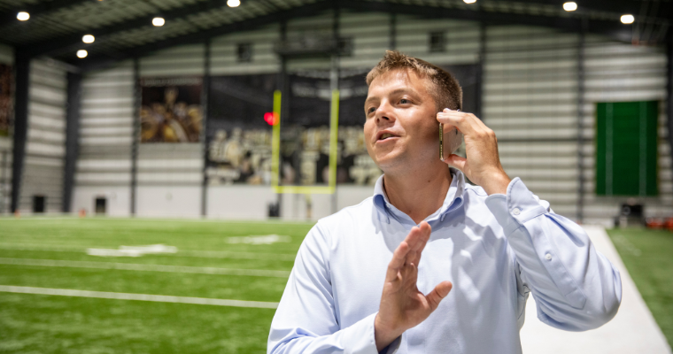 Sport Management program alumni William Fralia takes a business call while standing in the New Orleans Saints practice stadium.