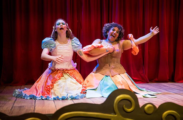 Two UL Lafayette students sit side-by-side on the stage while displaying opposite emotions