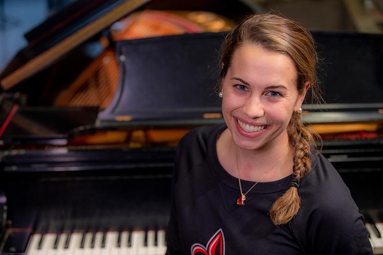 Music education major smiles at a piano