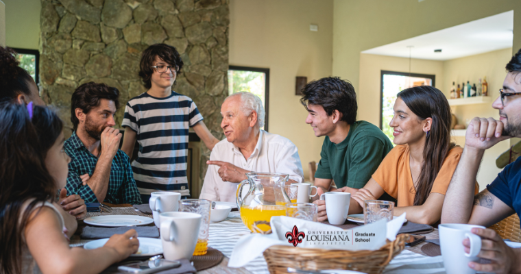 A family gathered around the dinning table talking with grandpa being the lead