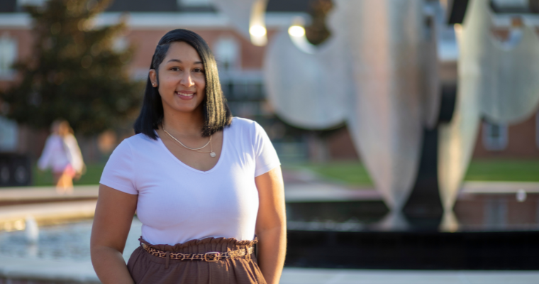 A portrait of Ashley Birotte, enrollment specialist for UL Lafayette Online, in front of the fleur-de-lis fountain on UL Lafayette's campus.