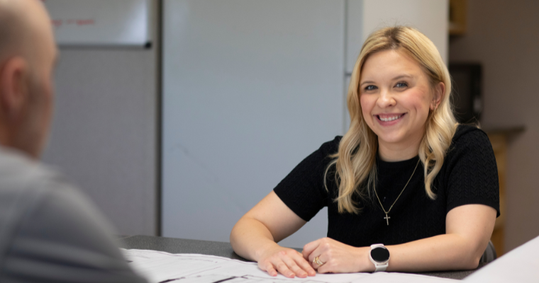 MBA online graduate smiles while collaborating with a business partner. 