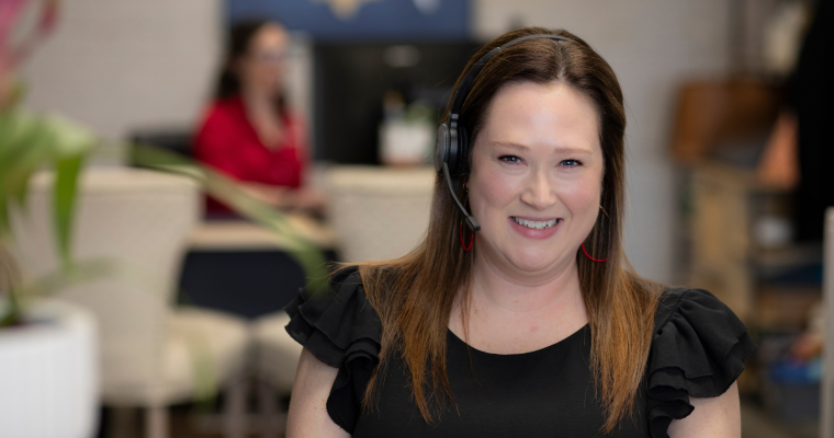 UL Lafayette online student smiles as she takes a call via headset.