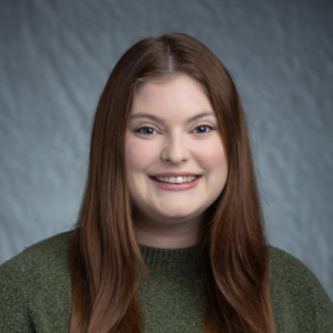 Headshot: Kathryn Gumfory pictured on a blue/gray background.