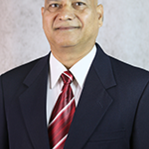 Portrait photograph of Dr. Adhikari in a black suit and a white button down shirt with a red tie.