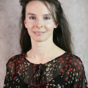 Portrait photo of Brandi Guidry-Hollier smiling wearing a black blouse with designs.