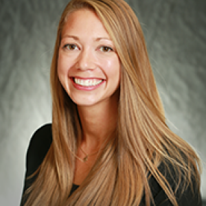 Portrait photograph of Stacy Bergeron smiling wearing a black dress and a black blazer.