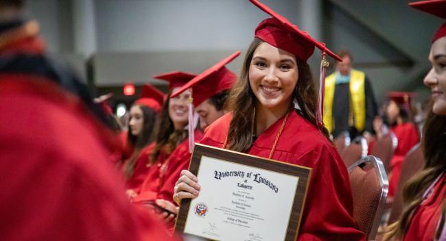 Madeline Cassedy holds up her degree plaque during commencement. Cassedy earned her degree in Health Promotion and Wellness at UL Lafayette.