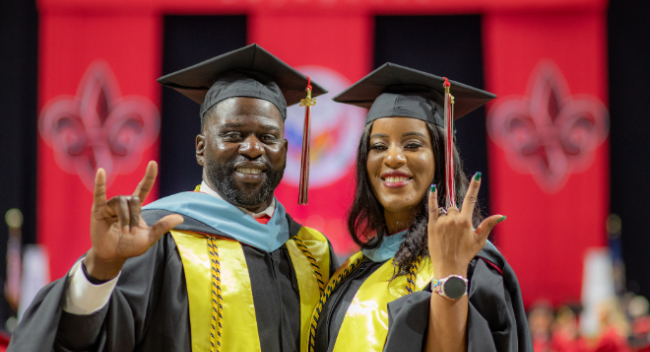 Kreig and Rekeisha Triggs stand in the Cajundome in black cap and gowns during commencement.