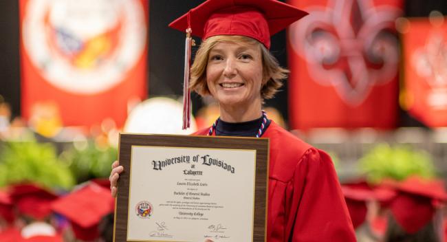 Lauren Lewis holds up her degree plague during commencement exercises. Lewis, a veteran, earned her bachelor's in general studies online from UL Lafayette.