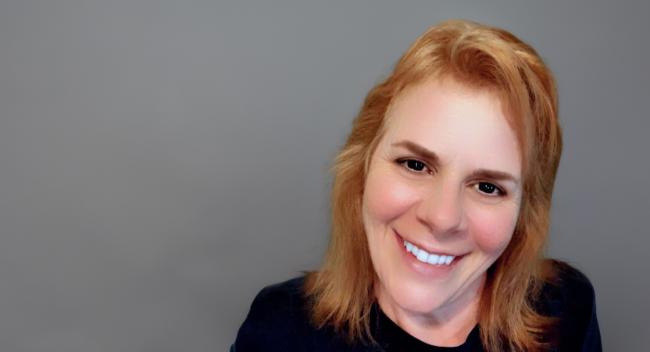Laurie Martin, MBA student, is pictured in a black shirt on a gray background.