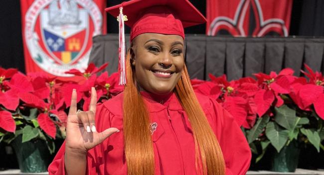 Latasha Cooper, 2023 graduate of UL Lafayette's online RN to BSN program, smiles and holds up the U-L hand sign at Commencement.