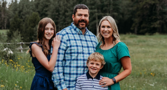 MBA online grad Jonathan Boudreaux smiles for outdoor family photo with wife, daughter, and son