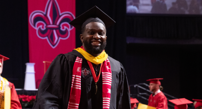 M.S. in Systems Tech graduate smiles in cap and gown after walking across the stage