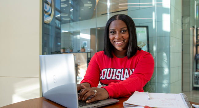 MSN graduate Shantell Dugas smiles for photo while studying in a red UL Lafayette t-shirt.