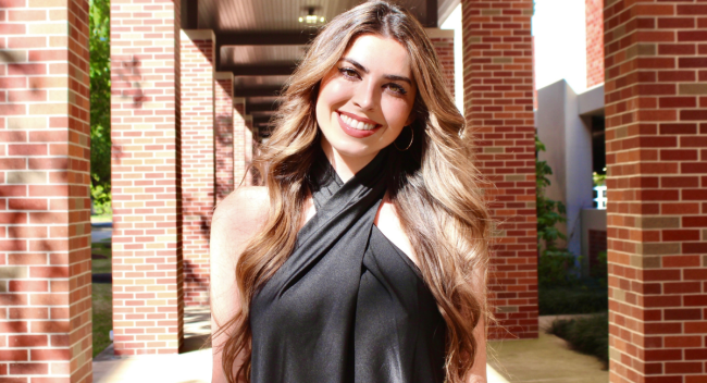 Online M.S. in Informatics graduate, Kaitlin Lange, smiles for photo under a UL Lafayette walkway