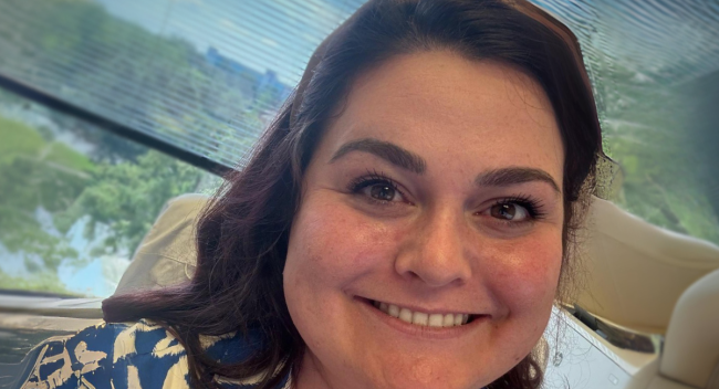 RN to BSN graduate Ashlynn Capace smiles for photo, sitting in front of an open window