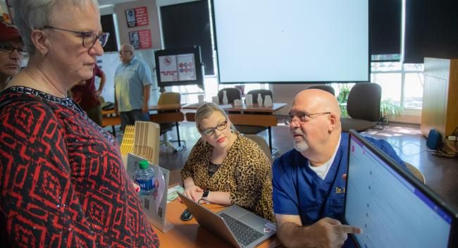 Penny Powell, Latasha Holt, and Robert Garrie gather around a computer monitor as Robert Garrie explains his Faculty Learning Community's research.