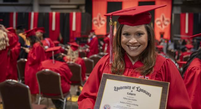 RN to BSN graduate Tiffany Soudelier smiles at Commencement while holding her new diploma.