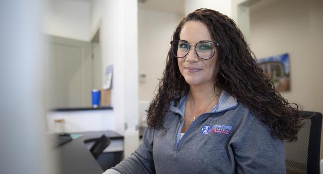 Health Services Administration graduate Sarah Beard smiles at the front desk of Family & Sports Chiropractic.