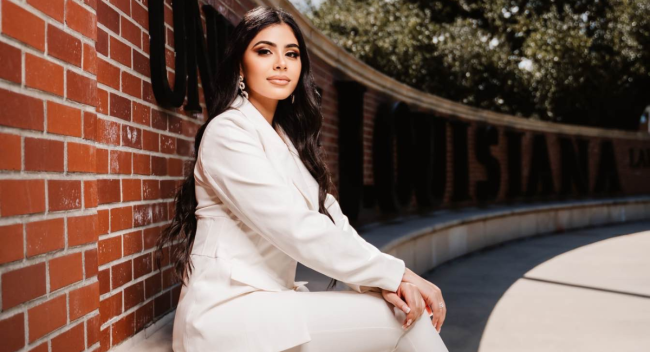 Tala Tobeh sits in front of the UL Lafayette wall. A graduate of UL Lafayette’s criminal justice online program, she now works with the state's fusion office.