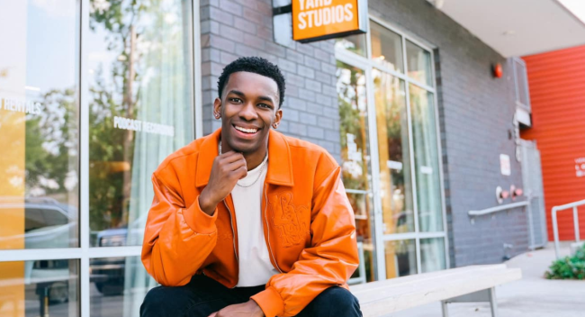 Online general studies grad Cameron Theyard smiles in front of his office space, The Yard Studios.