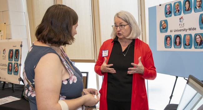 Instructional Technologist Renee Fiser is pictured in front of a research poster presentation as she speaks to a woman attending the FLC Showcase.