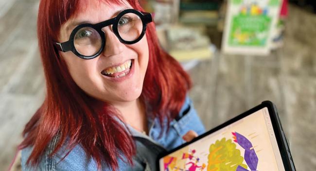 Artist Denise Gallagher holds up an illustration from her recent book project.