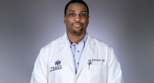 MBA in Health Care Administration online graduate smiles for headshot in white medical coat.