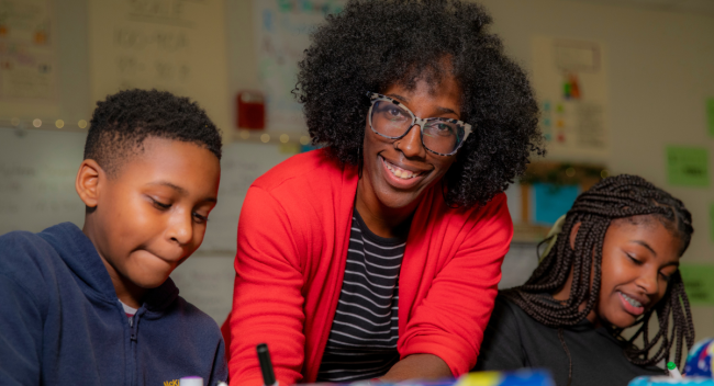 Denise Mallard, alumna of UL Lafayette's online Master of Education program, smiles as she works with two of her students.