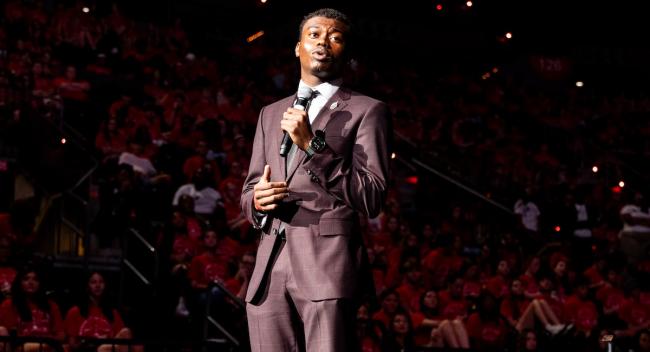 Student Tafari Beard stands on a stage with a microphone at new student convocation.
