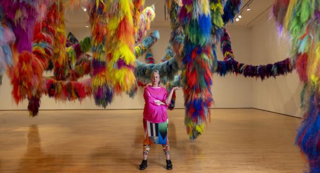 Artist Hrafnhildur Arnardóttir (aka Shoplifter) with their work Nervescape VII, a colorful, tactile art installation at the Hilliard Art Museum.