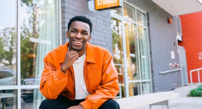 Online general studies grad Cameron Theyard smiles in front of his office space, The Yard Studios.