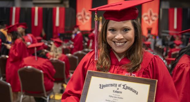 RN to BSN graduate Tiffany Soudelier smiles at Commencement while holding her University diploma.