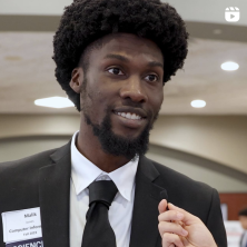 Black American male student in a black suit and sporting a name tag for a career fair 
