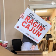 caucausian lady with a "The newest Ragin Cajun" sign up