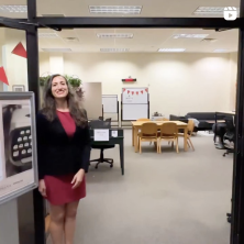 A staff member stands near the entrance of a room with a table in it.  