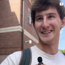 Man wearing a white shirt and backpack smiling