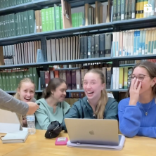 Several girls in the library laughing towards an interviewer